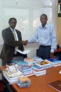 David Musoke (right) presents educational materials to Dr William Bazeyo, Dean of the Makerere University School of Public Health, Uganda
