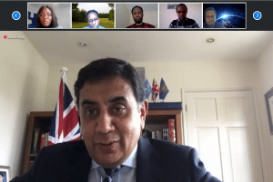 Lord Ahmad speaking from an office in a videoconferencing call with other call participants.