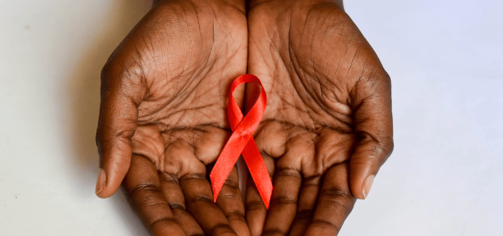 Hands holding red ribbon for HIV