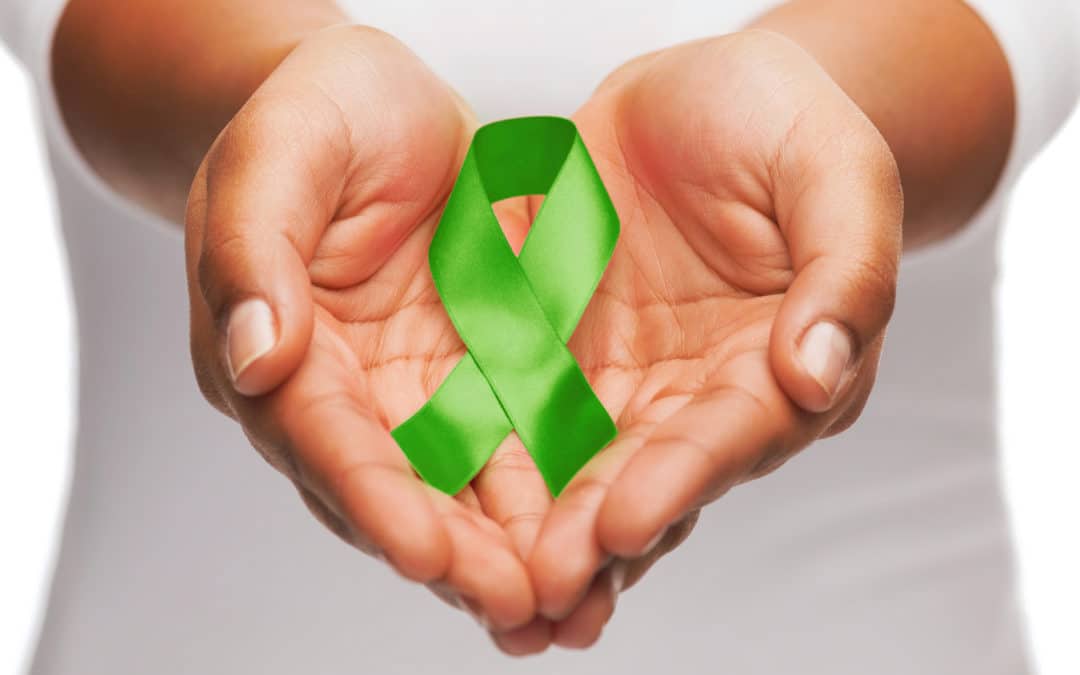 Female hands holding green mental health awareness ribbon