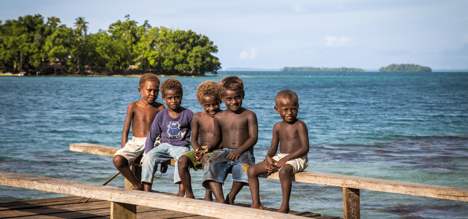 Group of children sitting on a wooden pier in Soloman Islands