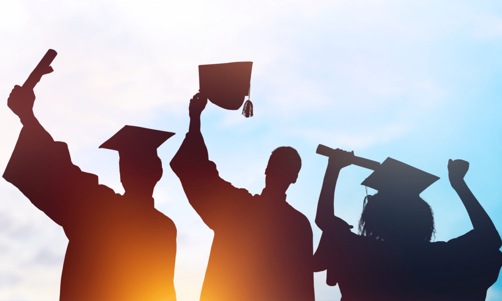 Silhouette of three students in graduation gowns and hats