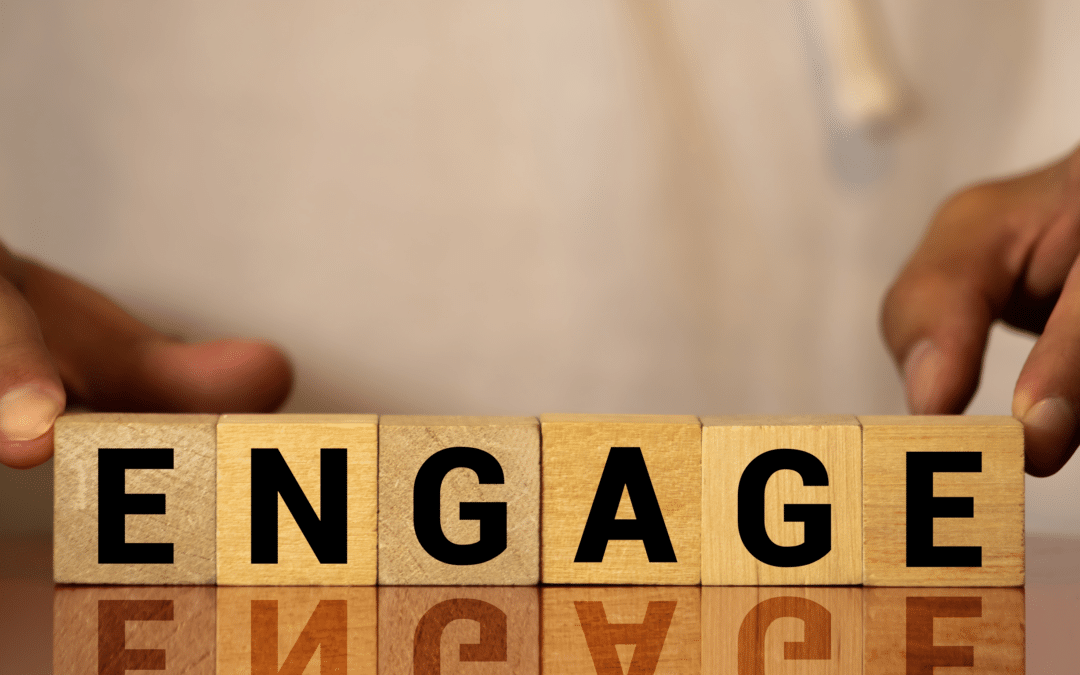 Hands positioning building blocks spelling the word 'ENGAGE'.