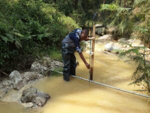 Photo of Emmanuel measuring the flow rate of a river to assess its hydro-power potential