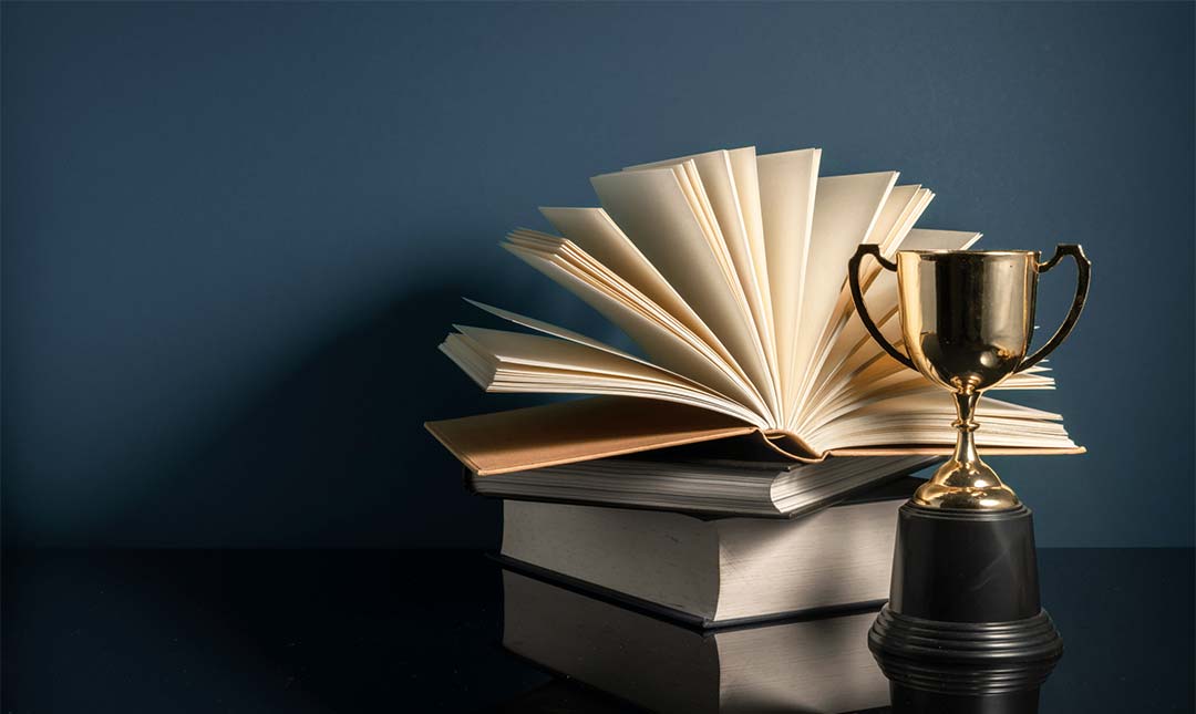 Metal trophy next to fanned books on table.