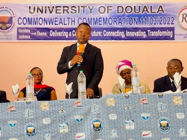 Panel photo of Alumni in Cameroon standing with microphone to mark Commonwealth Day
