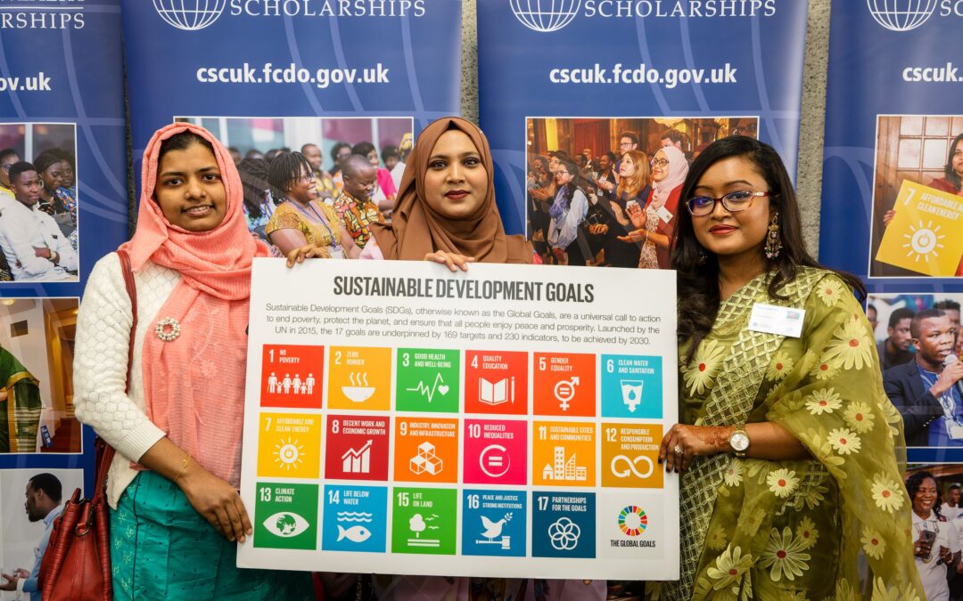 Three Scholars holding a sign showing the Sustainable Development Goals (SDGs) at a CSC event.