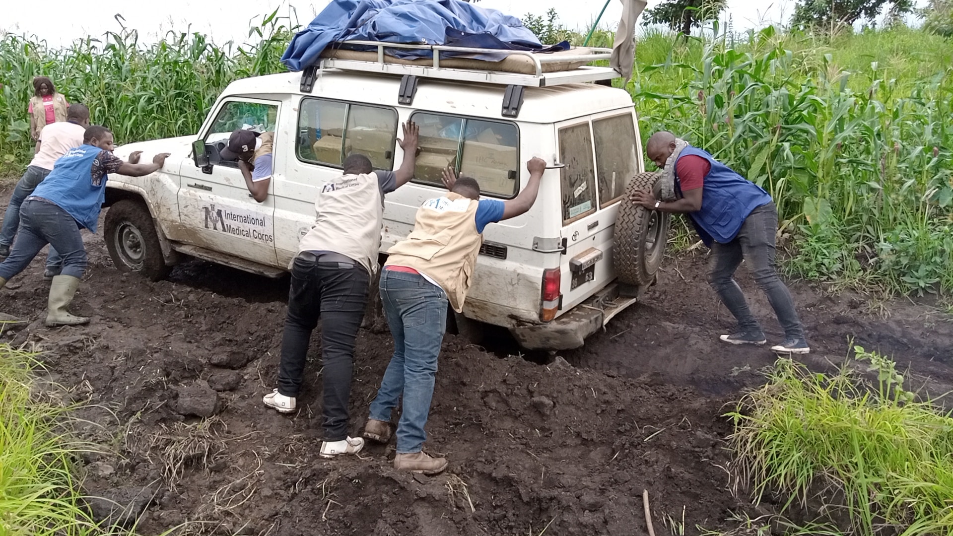 Members of the IMC push a truck carrying medical workers and supplies in rough terrain