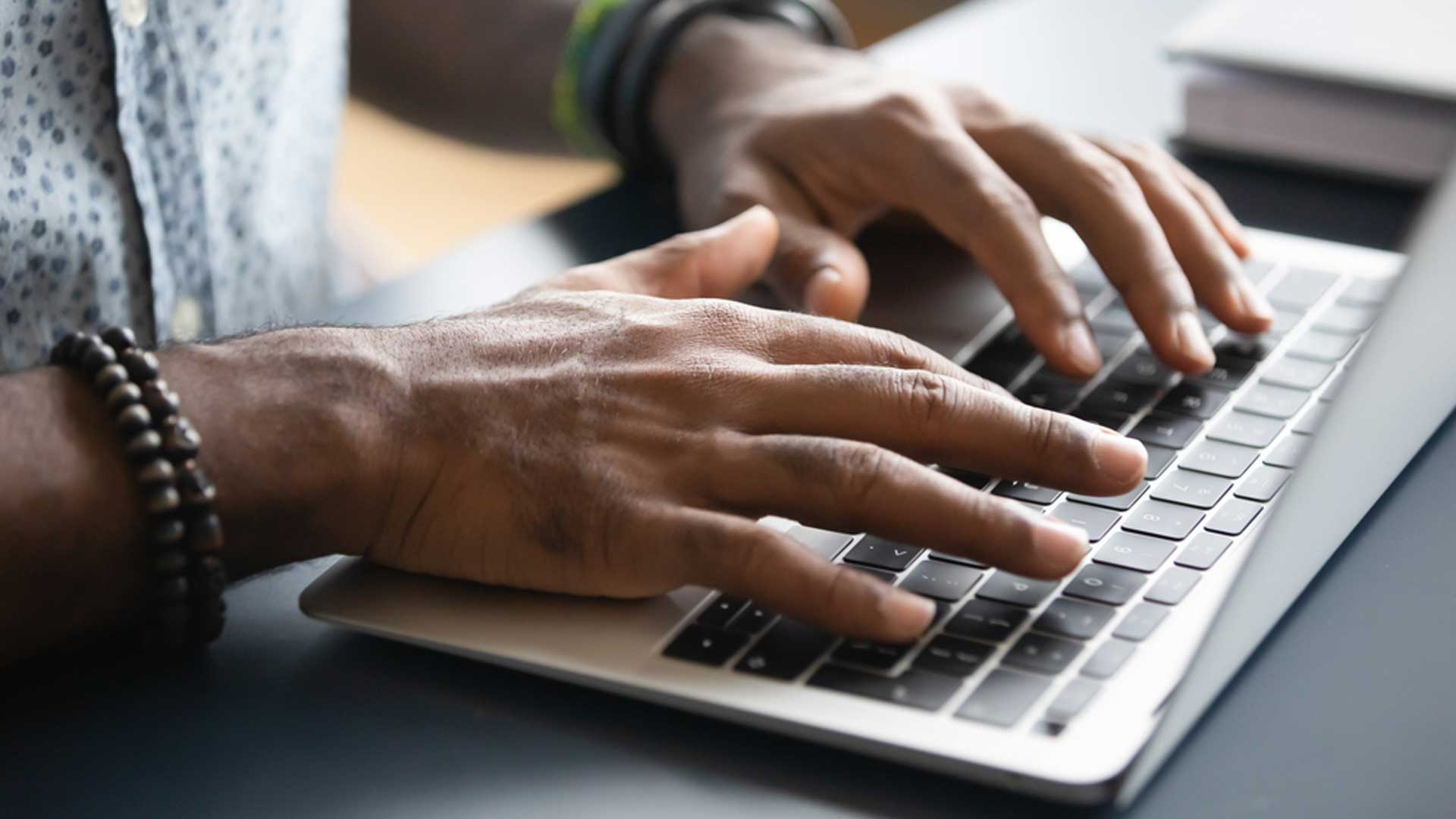 A person using a keyboard on a laptop, looking at the Commonwealth Scholarships FAQs.