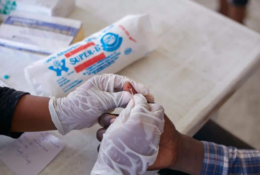 Close-up of hands in medical gloves taking a blood sample from a patient's hand.