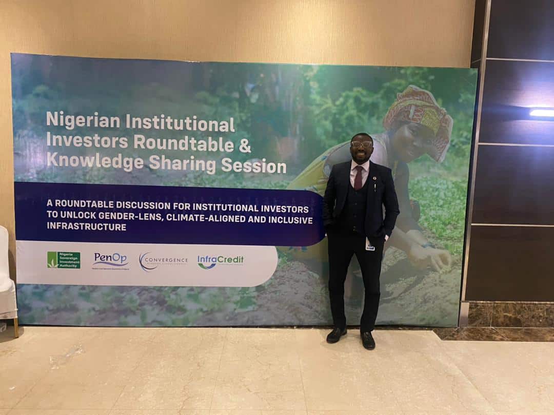Abbas standing beside a conference banner at the Nigerian Investors Roundtable Discussion
