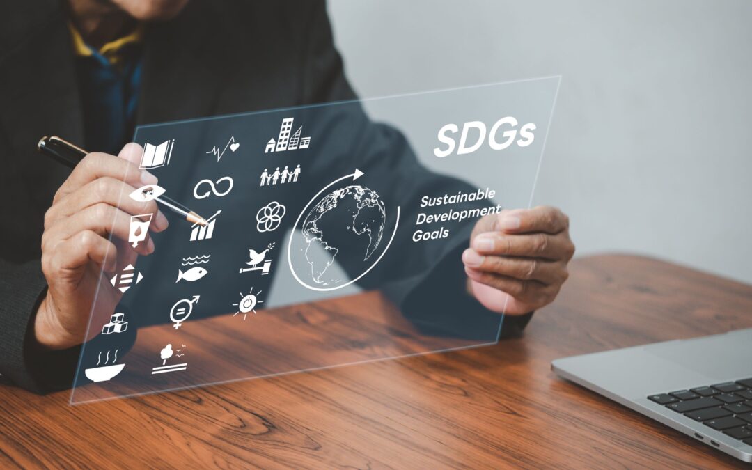 Man sitting at a table holding an interactive virtual interface with SDG icons.