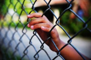 Young girl's hand on wire fence