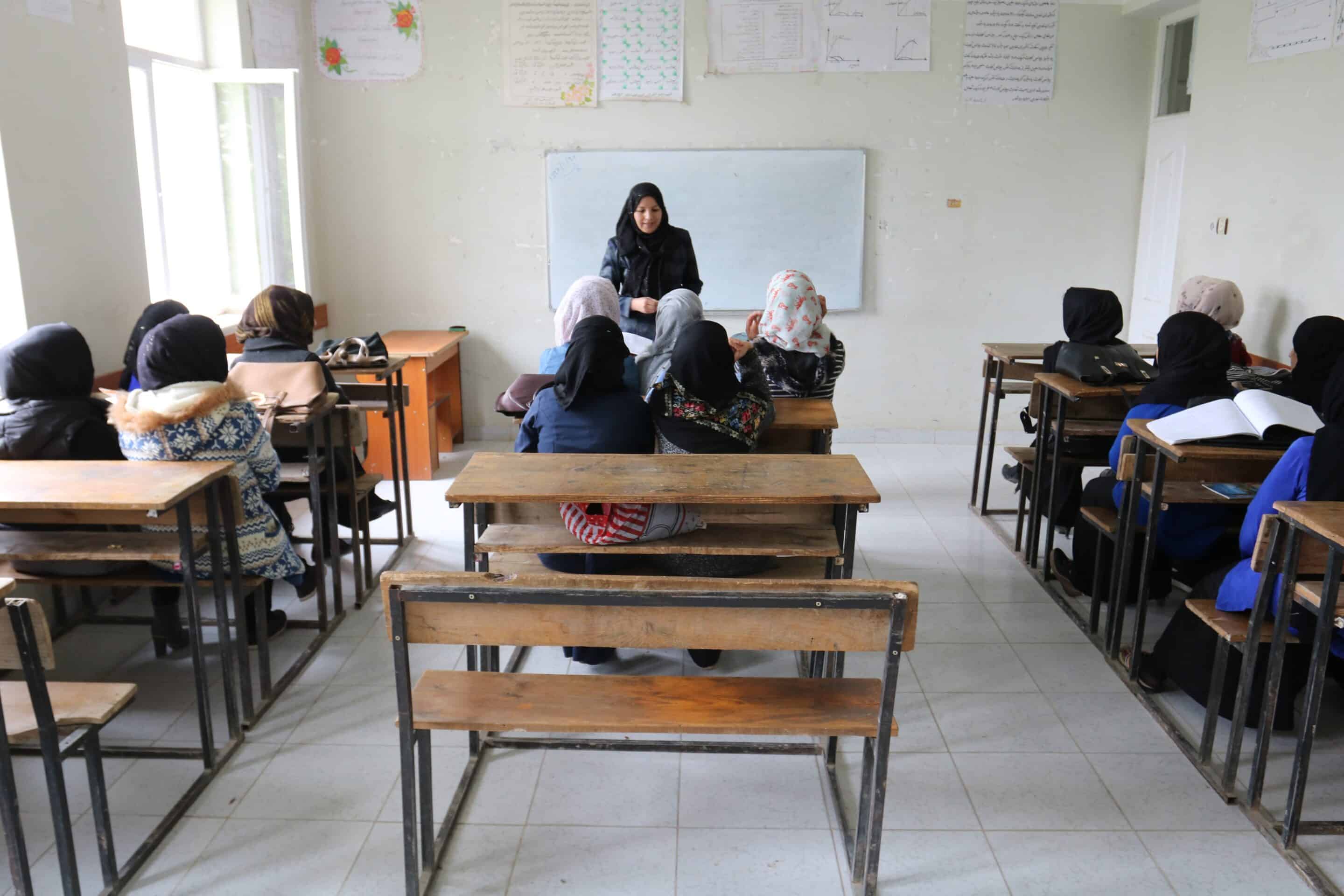 An Afghan female teacher teaching girls in a classroom