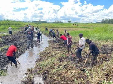 Community members opening drainage to divert excess water from local households